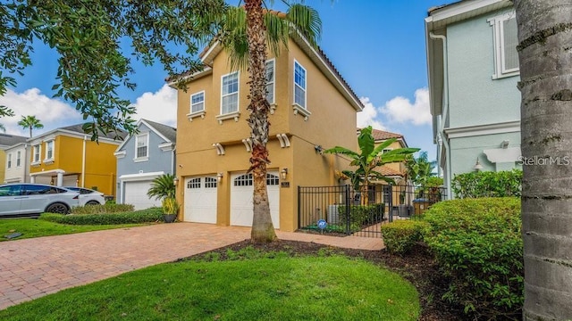 view of front of home with stucco siding, decorative driveway, a garage, and fence