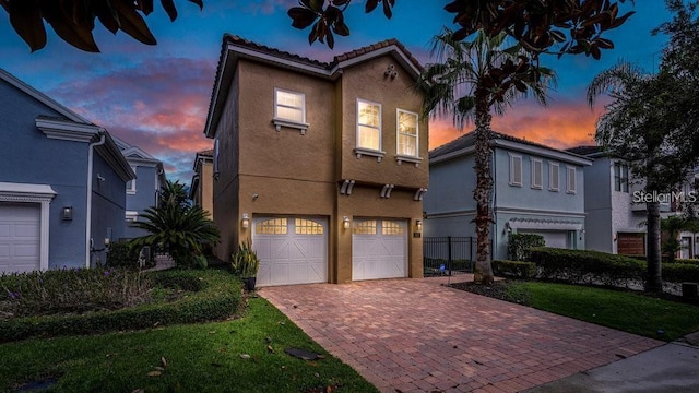 view of front of house featuring decorative driveway, a garage, and stucco siding