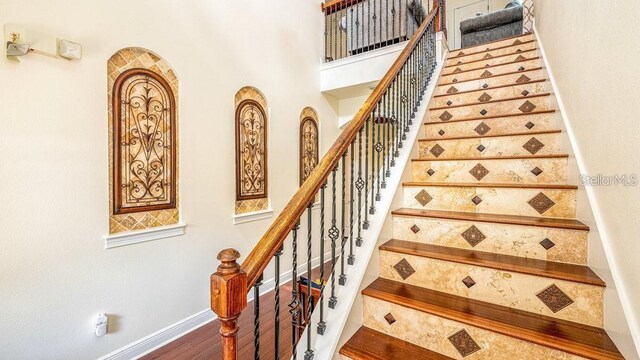 stairway with wood finished floors and baseboards