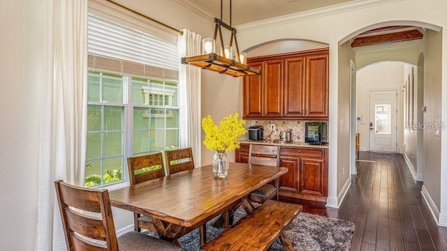 dining space featuring baseboards, ornamental molding, a wealth of natural light, arched walkways, and dark wood-style flooring