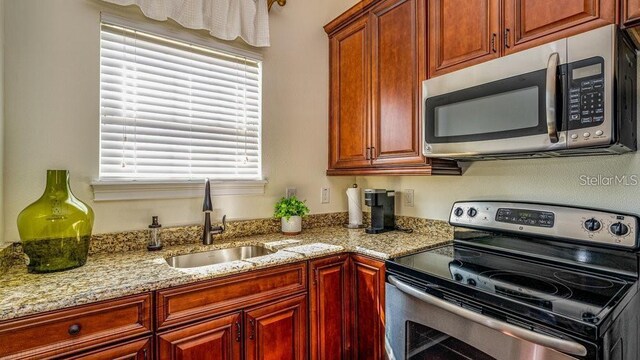 kitchen with light stone counters, appliances with stainless steel finishes, and a sink