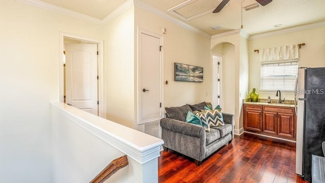 sitting room with arched walkways, a ceiling fan, ornamental molding, and dark wood-style flooring