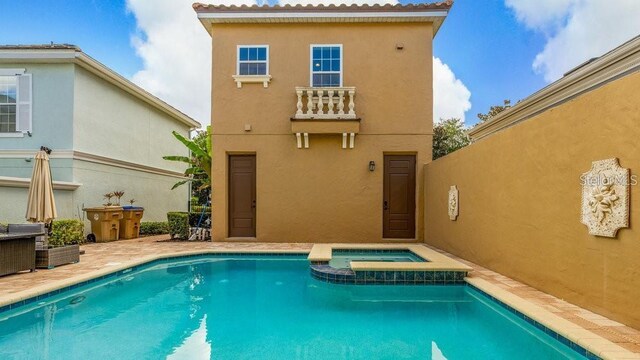 back of property with stucco siding and a pool with connected hot tub