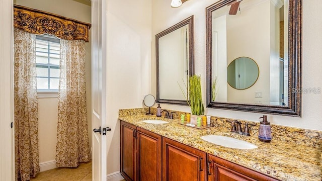 bathroom featuring a sink, baseboards, and double vanity