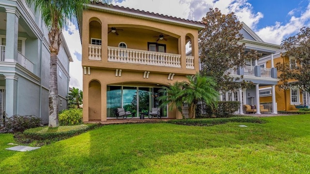 rear view of property featuring a patio area, stucco siding, a ceiling fan, and a yard