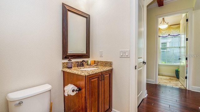 bathroom featuring baseboards, toilet, vanity, and hardwood / wood-style flooring