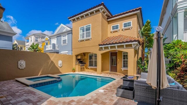 back of property with stucco siding, a pool with connected hot tub, a patio, fence, and a tiled roof