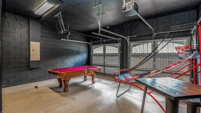 playroom featuring pool table, concrete block wall, electric panel, and a garage