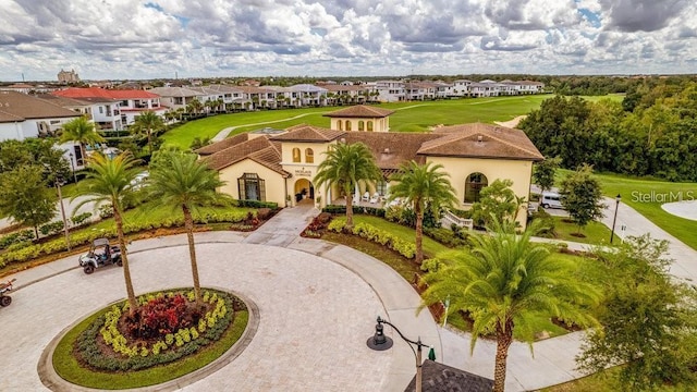 mediterranean / spanish-style home with stucco siding, a residential view, curved driveway, and a tiled roof