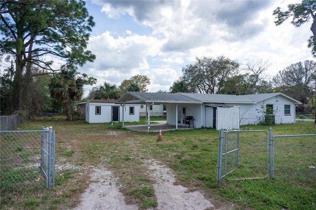 single story home with a front lawn, fence, metal roof, driveway, and a gate