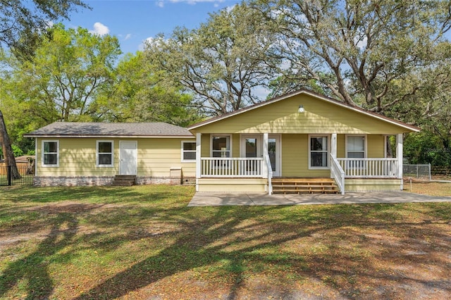 view of front of home with entry steps, covered porch, a front lawn, and fence