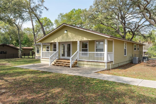 view of front of property featuring a front lawn, fence, a porch, central AC unit, and french doors