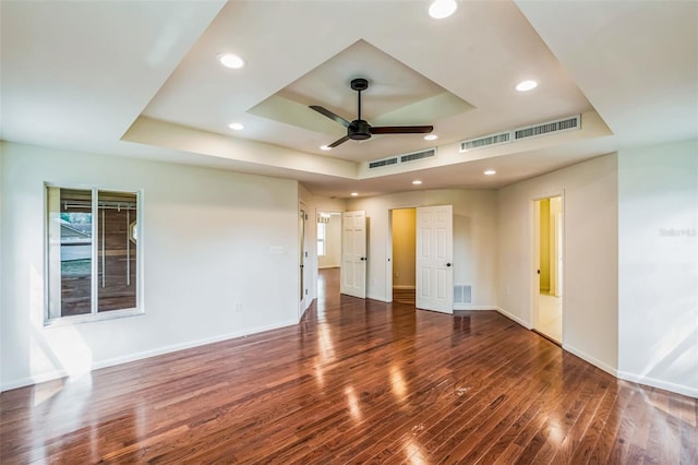 spare room with visible vents, baseboards, a tray ceiling, and wood finished floors