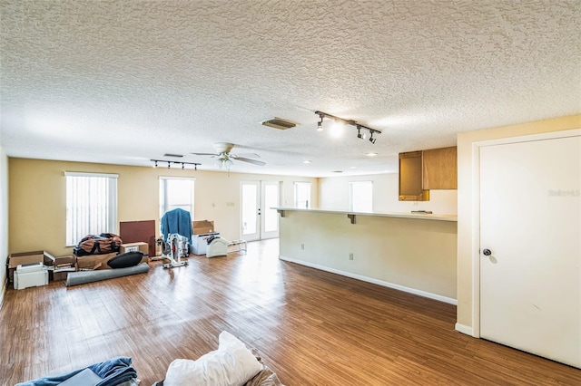 living area featuring visible vents, a ceiling fan, a textured ceiling, wood finished floors, and baseboards