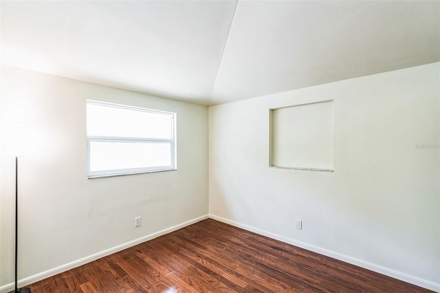 unfurnished room featuring vaulted ceiling, baseboards, and wood finished floors