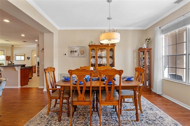 dining room with baseboards, recessed lighting, arched walkways, crown molding, and light wood-type flooring