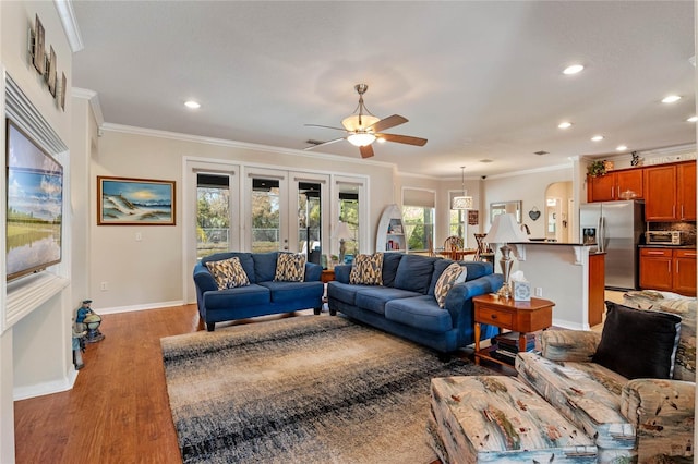 living room featuring recessed lighting, baseboards, ornamental molding, and light wood finished floors