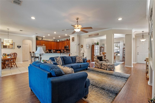 living room featuring light wood finished floors, visible vents, arched walkways, and baseboards