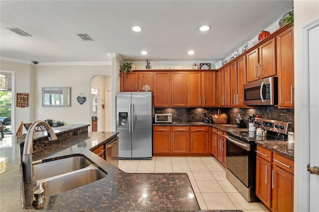 kitchen featuring visible vents, a sink, arched walkways, appliances with stainless steel finishes, and light tile patterned flooring