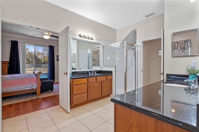 ensuite bathroom with tile patterned flooring, a stall shower, visible vents, and a sink