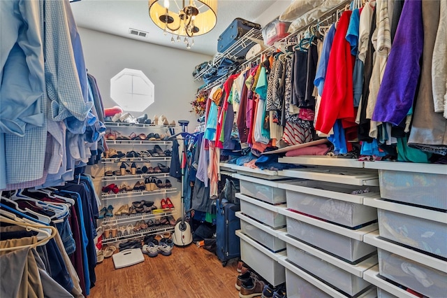 walk in closet featuring visible vents, an inviting chandelier, and wood finished floors