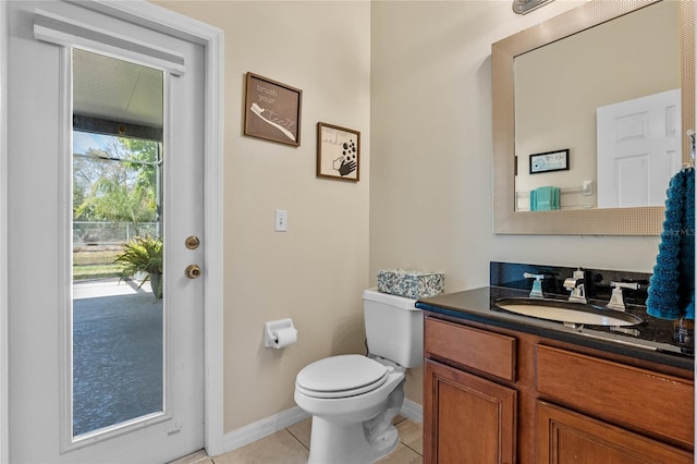 half bath featuring tile patterned flooring, toilet, vanity, and baseboards