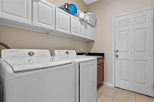 clothes washing area with washer and clothes dryer, light tile patterned floors, cabinet space, and baseboards