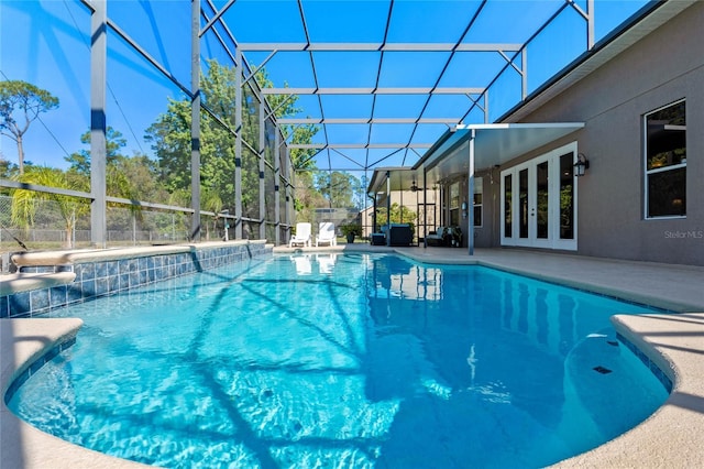 pool with a lanai, a patio area, and french doors