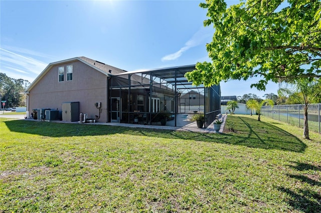 rear view of house with glass enclosure, a yard, central AC unit, and fence