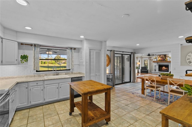 kitchen with electric range, a sink, backsplash, a fireplace, and ceiling fan