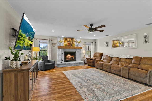 living area with visible vents, a brick fireplace, recessed lighting, wood finished floors, and a ceiling fan