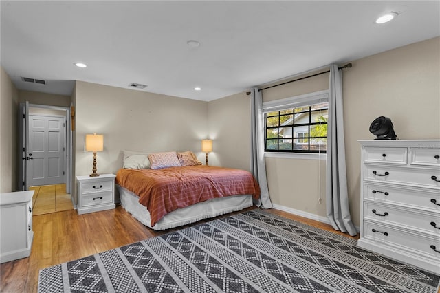 bedroom featuring light wood finished floors, visible vents, recessed lighting, and baseboards