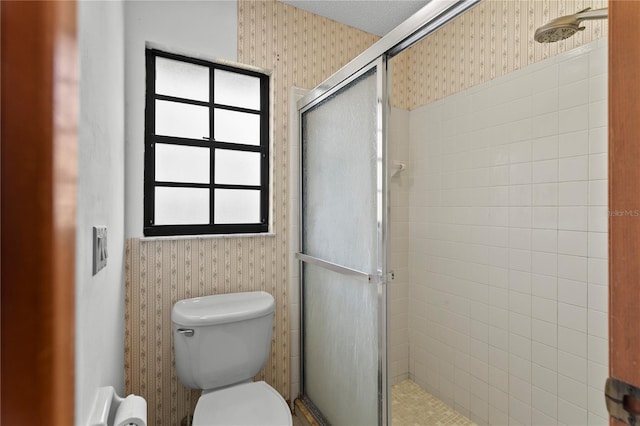 full bathroom featuring toilet, a shower stall, and wallpapered walls