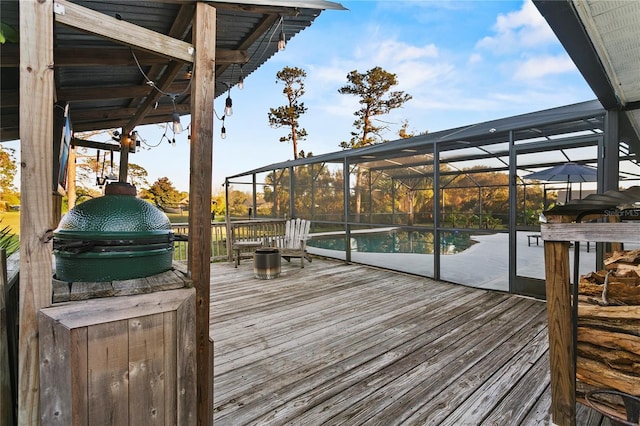 deck with an outdoor pool, glass enclosure, and area for grilling