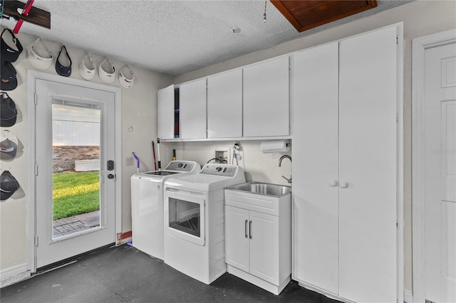 clothes washing area featuring a textured ceiling, a sink, cabinet space, and washing machine and clothes dryer