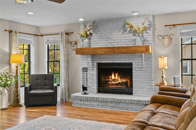 living area with a brick fireplace and wood finished floors