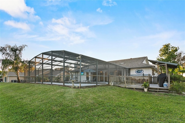 rear view of house featuring glass enclosure, a lawn, an outdoor pool, and a shingled roof