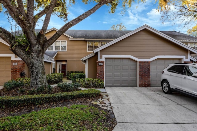 view of property featuring a garage, brick siding, and driveway