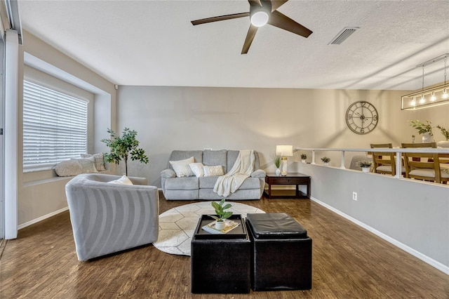 living area featuring baseboards, wood finished floors, visible vents, and a textured ceiling