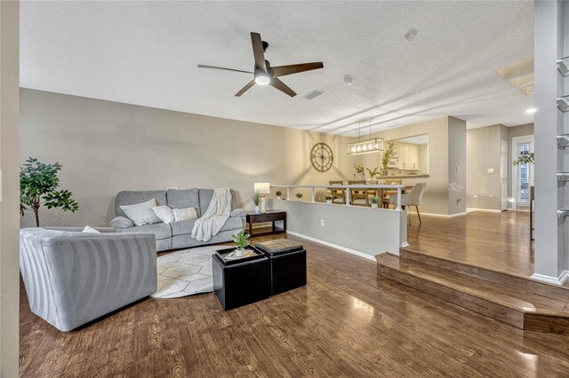 living area with visible vents, baseboards, a textured ceiling, and wood finished floors