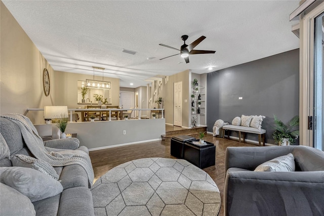 living area with visible vents, baseboards, a textured ceiling, and wood finished floors