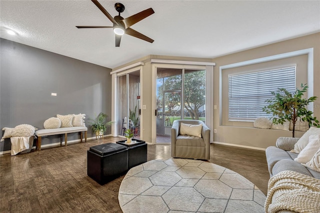 living room featuring a textured ceiling, baseboards, ceiling fan, and wood finished floors