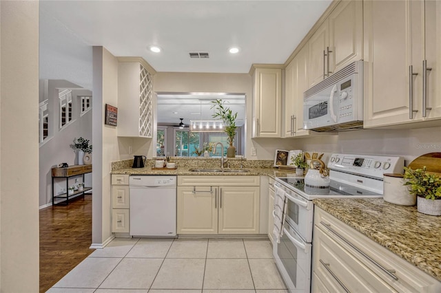 kitchen featuring white appliances, light stone countertops, visible vents, and a sink