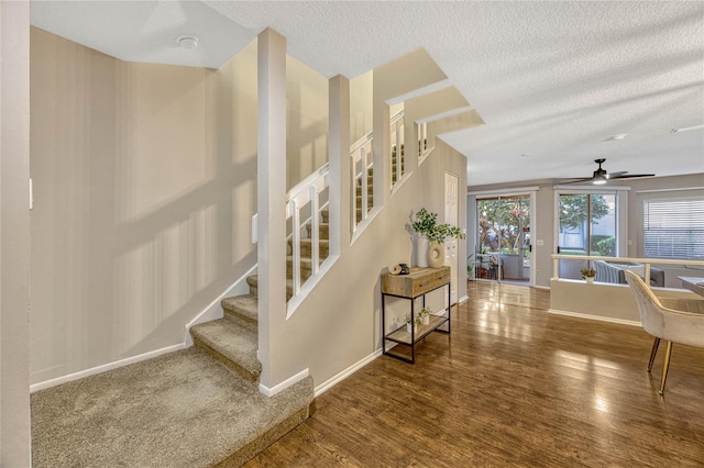 staircase featuring baseboards, a textured ceiling, and wood finished floors