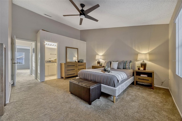 bedroom with light carpet, a textured ceiling, connected bathroom, baseboards, and ceiling fan