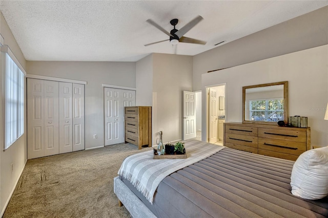 carpeted bedroom with visible vents, two closets, a ceiling fan, a textured ceiling, and lofted ceiling