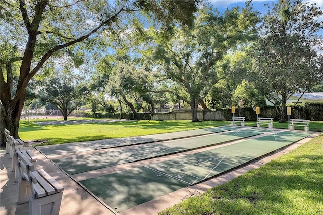 view of home's community with shuffleboard, a lawn, and fence