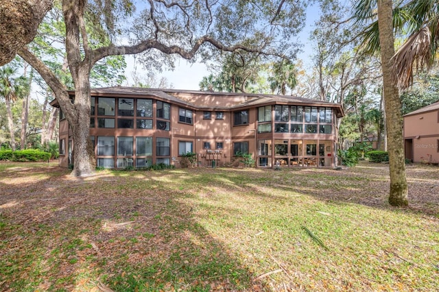 back of house featuring a lawn and a sunroom