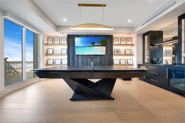 game room with recessed lighting, a raised ceiling, and wood finished floors