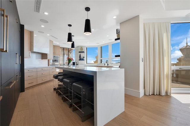 kitchen with light wood finished floors, visible vents, a kitchen island, light countertops, and modern cabinets